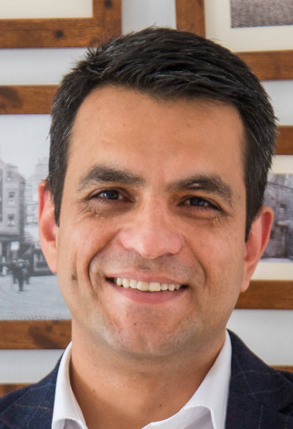 Airbnb Hosting A man smiling while hosting in front of framed pictures.