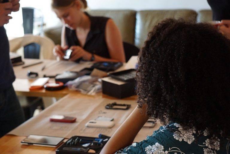 Airbnb Hosting A group of people hosting an Airbnb gathering around a table working on a cell phone.