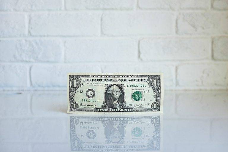 Airbnb Hosting An Airbnb hosting setup with a one dollar bill on a white table, featuring a brick wall backdrop.